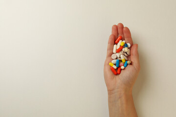 Female hand hold different pills on white background