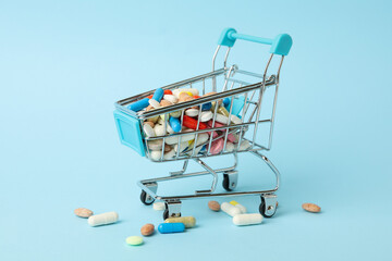 Shop cart with different pills on blue background