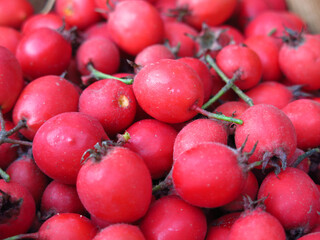 scattering of red hawthorn berries lie in a basket