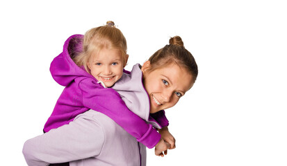 Smiling blonde kid girl and woman in stylish jumpsuits with hood posing over gray background. Cute daughter 4-5 year old hugging her mother. Mock up copy space lifestyle concept.