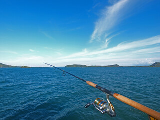 fishing rods and reels with a background of blue sea and islands