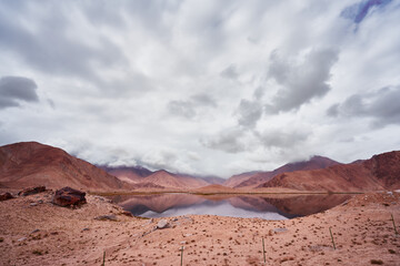 Lake surround by mountains with desert landscape and cloudy sky in Xinjian, China