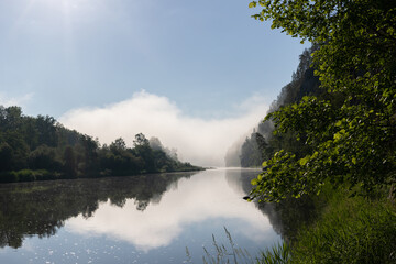 Fototapeta na wymiar Fantastic dramatic foggy river in morning sunny beams. Panoramic