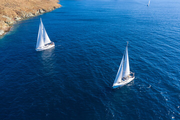 Sailing boats with white sails, rippled sea background