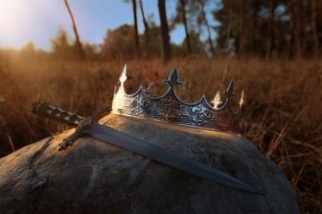 mysterious and magical photo of silver king crown and sword in the England woods over stone....