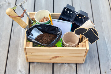 gardening, farming and planting concept - garden tools in wooden box and soil and pots