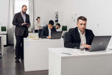 The senior Manager checks the quality of tasks performed by his Junior employees sitting at a...