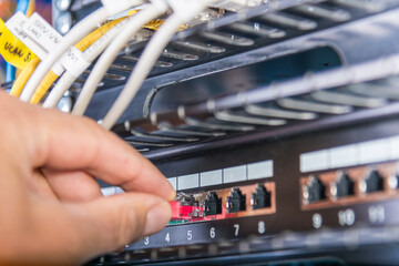 hand of engineer plugging in ethernet cable into server switch