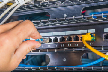hand of engineer plugging in ethernet cable into server switch