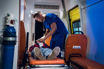 Medical student having an exam, giving an oxygen mask to his patient in an ambulance car.