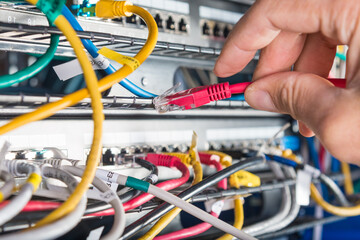 hand of engineer plugging in ethernet cable into server switch