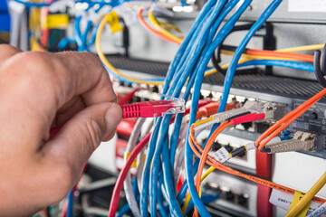 hand of engineer plugging in ethernet cable into server switch