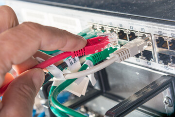 hand of engineer plugging in ethernet cable into server switch