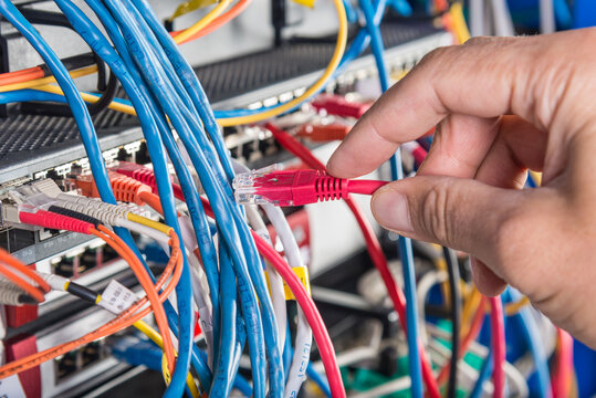 hand of engineer plugging in ethernet cable into server switch