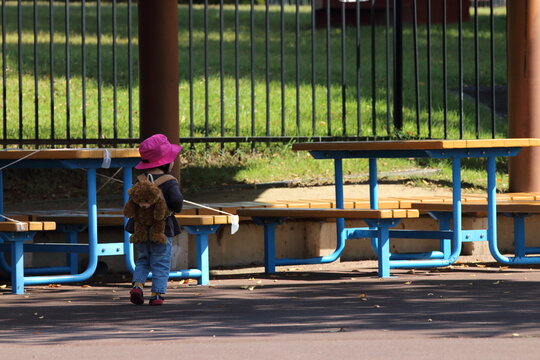 公園の通路を歩く帽子を被りバックを背負った男の子