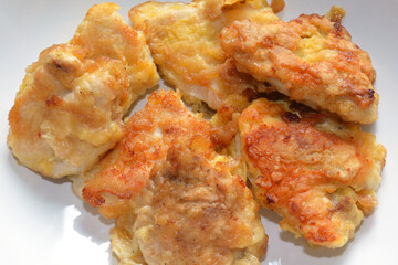 Ready-made breaded chicken fillet on white surface.