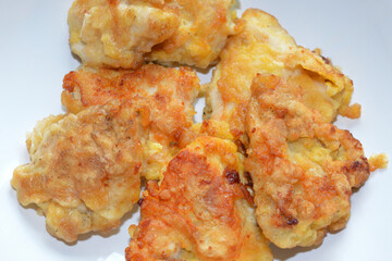 Ready-made breaded chicken fillet on white surface.