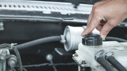  Hand checking level of coolant car engine.