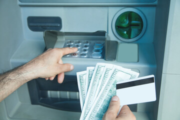 Hand holding dollars and credit card withdrawn from ATM.