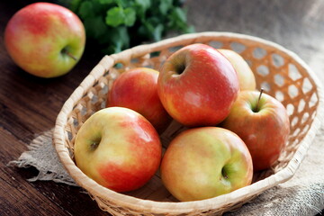 Apples in a wicker basket illuminated by the sun. Plain apples on a rustic table.