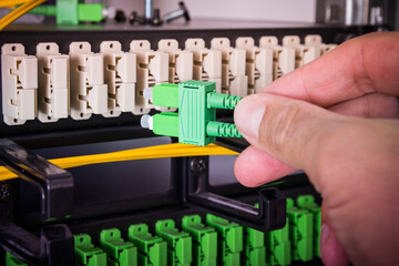 Hand of computer engineer connecting fiber optic cable in server