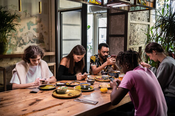 leisure, technology and people concept - group of happy international friends with smartphones in a cafe.