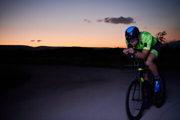 triathlon athlete riding bike fast at night
