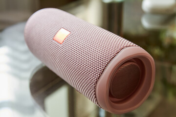 A part of portable pink bluetooth and wireless speaker on a glass surface. Close-up, selective focus