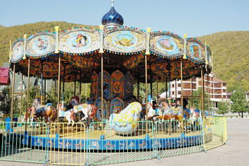 Carousel, a children's attraction in Sochi, Russia. View of mountain peaks