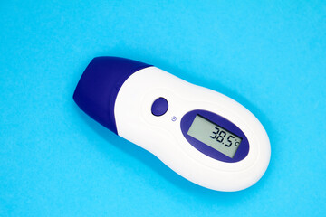 A non-contact infrared thermometer on blue background showing temperature 38.5