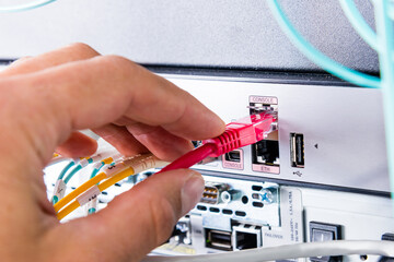 Hand of computer engineer connecting network cable in server cab