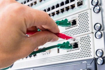 Hand of computer engineer connecting network cable in server cab