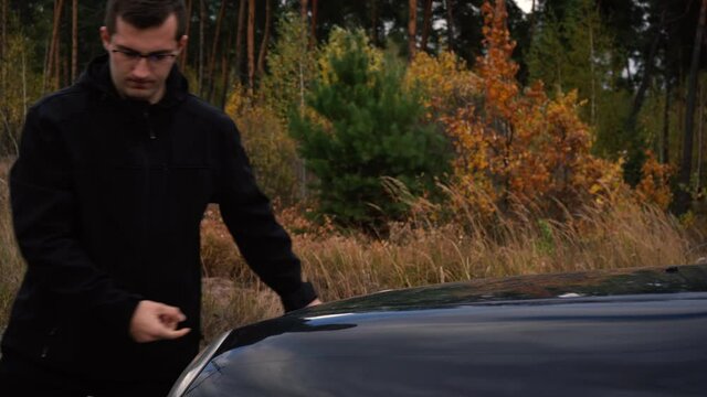 man lowers the hood of the car