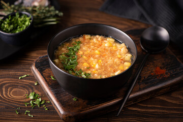 red lentil and corn soup with herbs and paprika in a black bowl