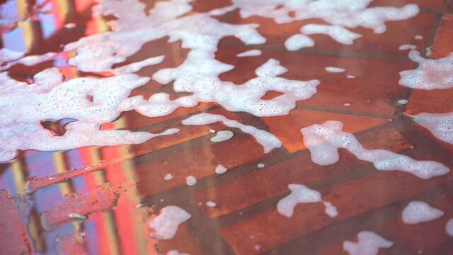 Water and soap foam from a car wash flowing down the garage