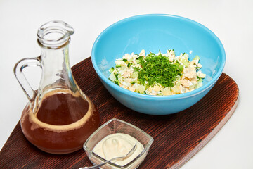 Traditional Russian cold soup with kvass, okroshka with ham, vegetables and sour cream on a wooden board