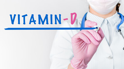 Close up female doctor writing word VITAMIN D with marker. Medical concept