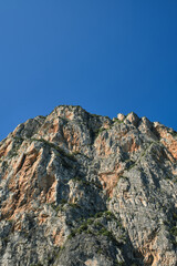 The tops of the yellow peaks of the rocks. Red stones on a blue background. Gray rocks at high altitude. Alps top on blue sky. Rough rocky stones.