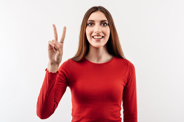 Portrait of a happy young woman with long chestnut hair showing peace gesture