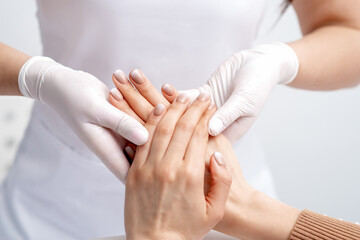 Manicurist wearing gloves doing wax massage on female hands with manicure in nail salon
