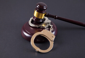 Police handcuffs and judge gavel on an isolated black background.