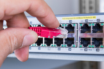 hand of network administrator plugging in network cable 