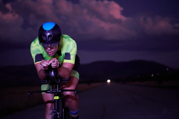 Obraz na płótnie Canvas triathlon athlete riding bike fast at night