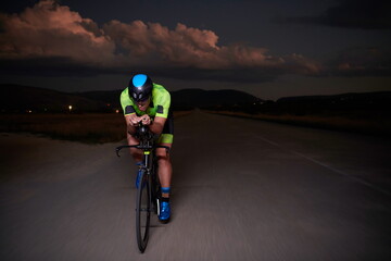 triathlon athlete riding bike fast at night