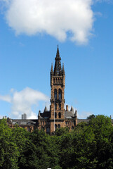 Fototapeta premium Ornate 19th century Gothic Stone Tower & Trees seen against Blue Sky 