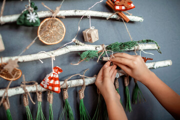 Girl near original Christmas tree made with branches, ecological toys, zero waste holidays