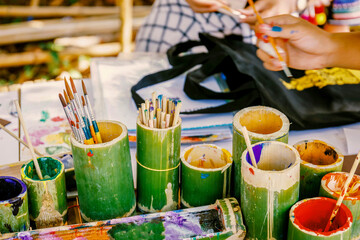 Many paintbrushes in fresh bamboo vase on table