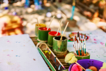 Many paintbrushes in fresh bamboo vase on table
