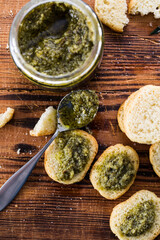 Top view of italian crostini with pesto genovese on brown wooden background.