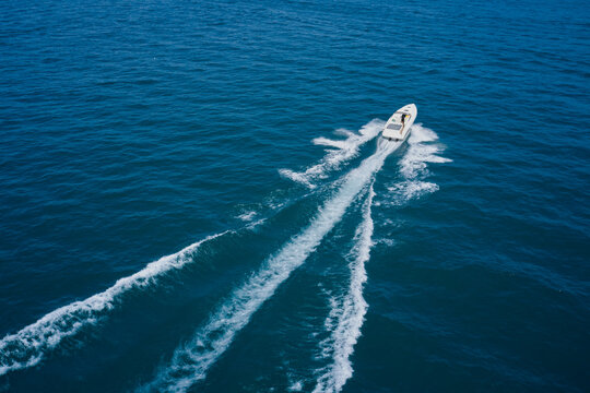 Top view of a white boat sailing to the blue sea. Aerial bird's eye view photo taken by drone of boat.  Motor boat in the sea.Travel - image.